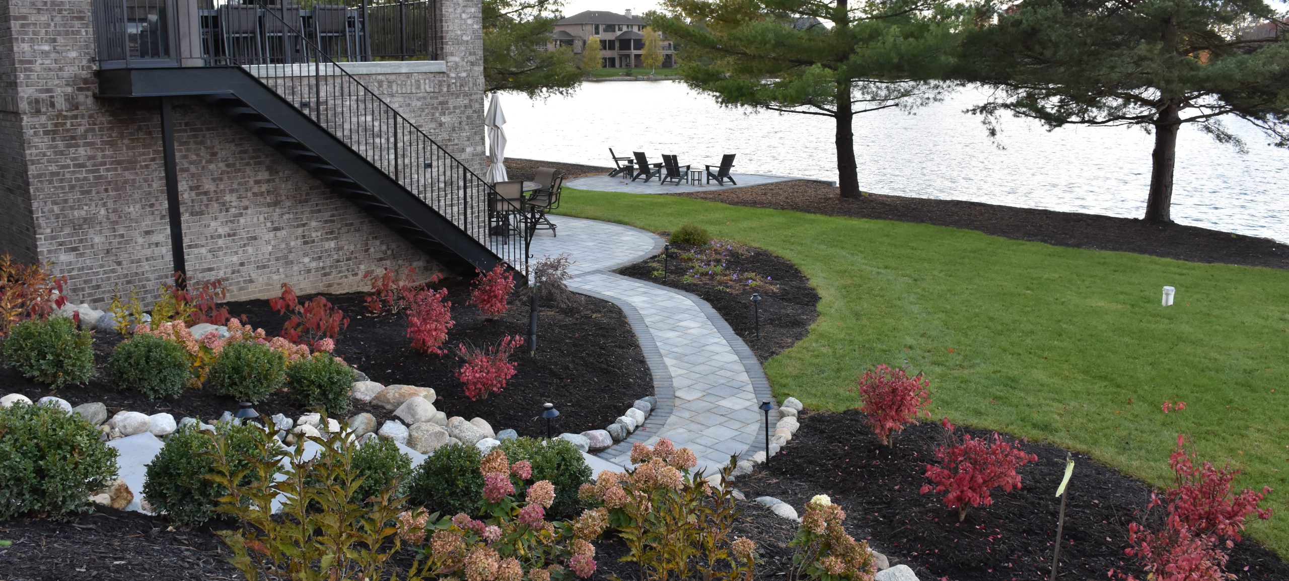 Landscape area with flower bed and walkway leading to stone building